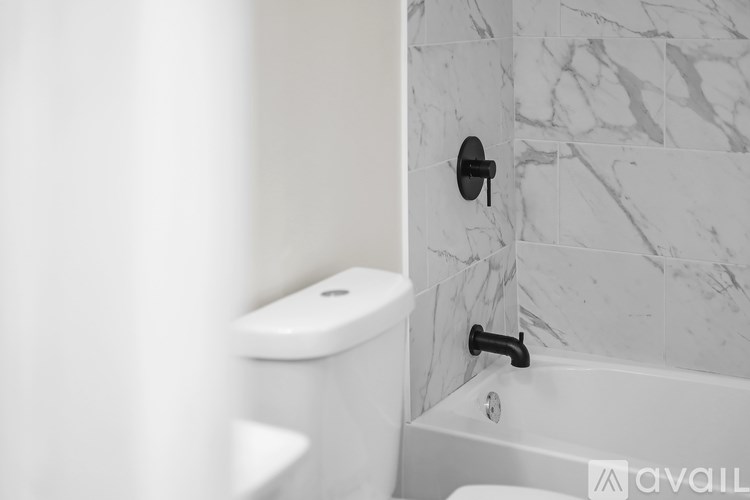 A white toilet and a white bathtub with a black handle.