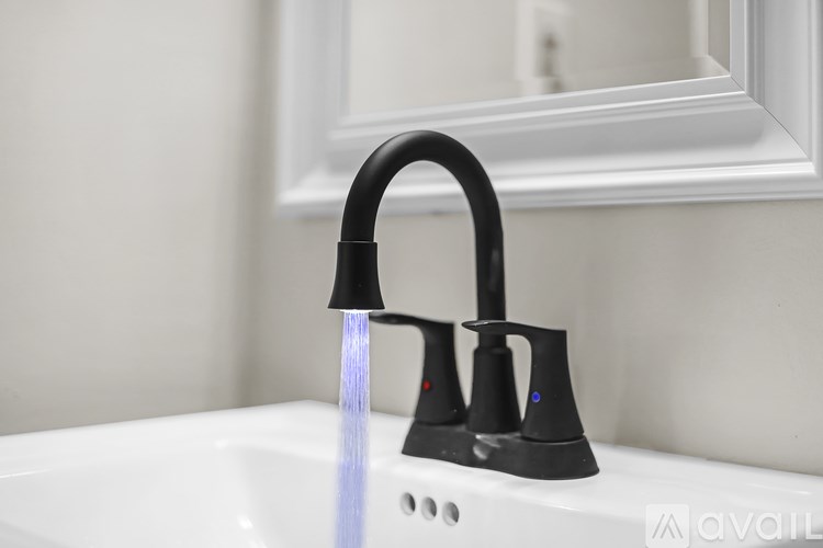A black faucet with a single stream of water flowing from it.