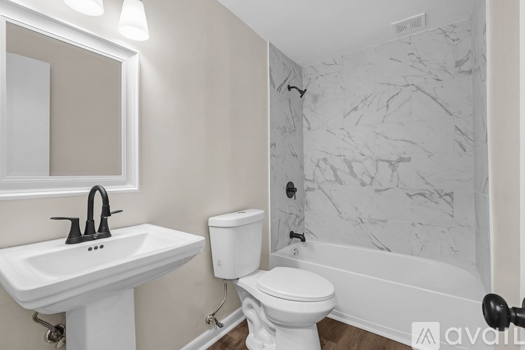 A white sink and toilet in a bathroom with a marble wall.