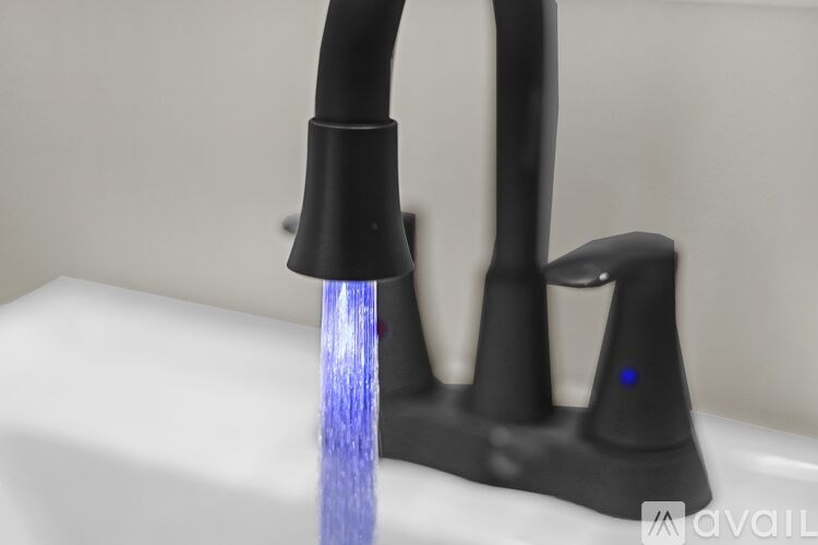 A black faucet with a blue light is turned on.