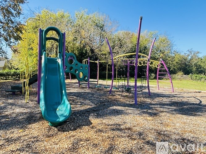 A playground with a green slide and purple swings.