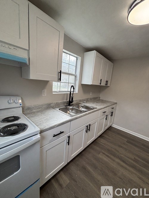 A kitchen with white cabinets and a stove top oven.