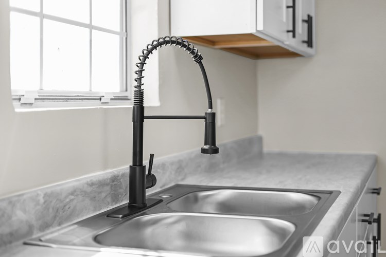 A kitchen sink with a black faucet and a window above it.