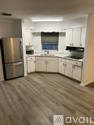 A kitchen with a refrigerator, microwave, oven, and sink.