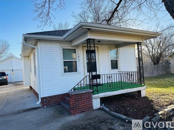 A small white house with a black railing on the front porch.