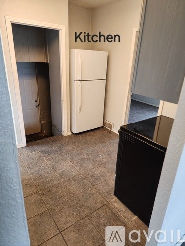 A kitchen area with a refrigerator and a trash bin.