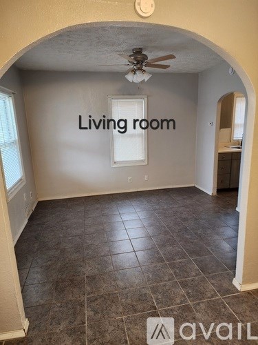 A living room with a ceiling fan and tile flooring.