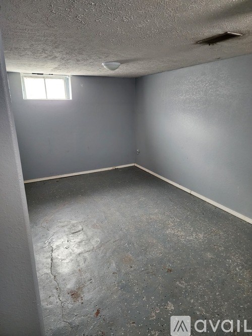 A room with a window and a dirty floor.