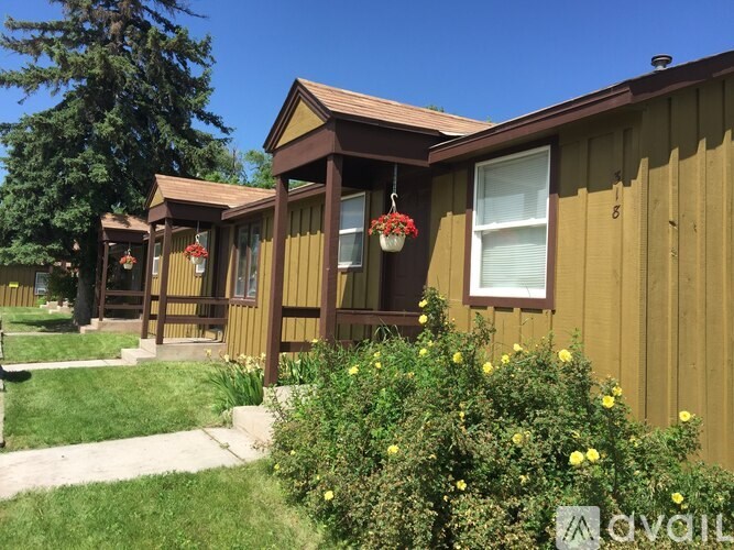 A house with a brown siding and a red flower hanging on the front door.