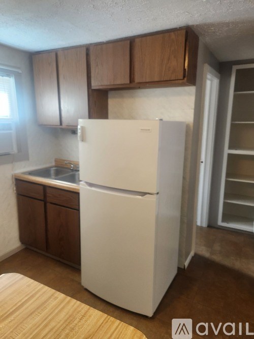 A white refrigerator in a kitchen with wooden cabinets.