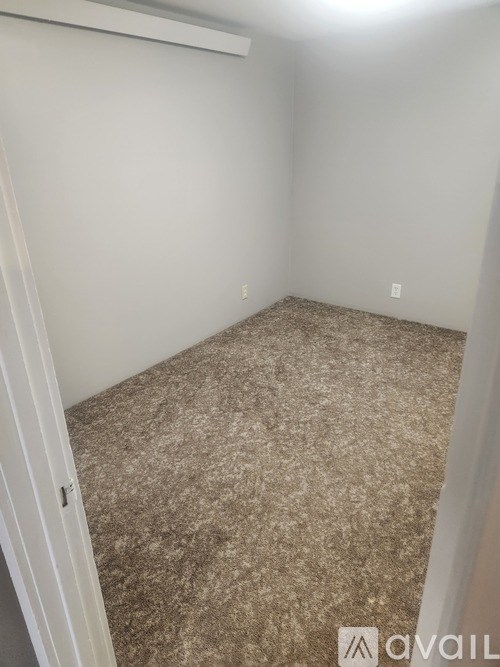 A room with a carpeted floor and a door on the left.
