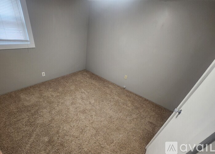 A room with a carpeted floor and a window with blinds.