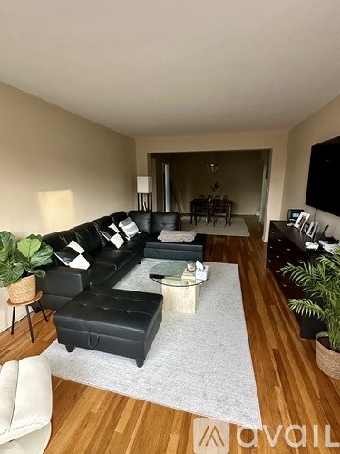 A living room with a black couch and a white chair.