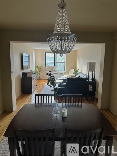 A dining room with a table set for two and a chandelier hanging from the ceiling.