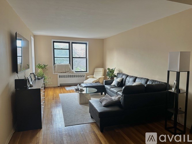 A living room with a black couch and a television on the wall.