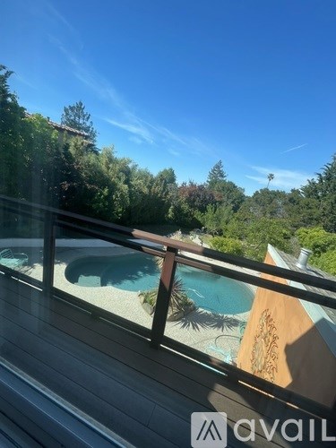 A wooden deck overlooks a pool and a lush green landscape.