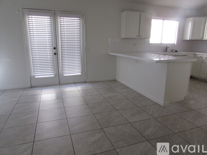 A kitchen with white cabinets and a white island with a sink.