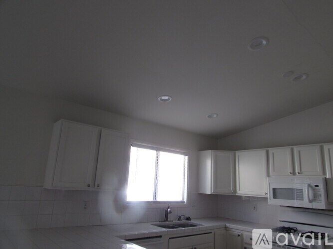 A kitchen with white cabinets and appliances is available.
