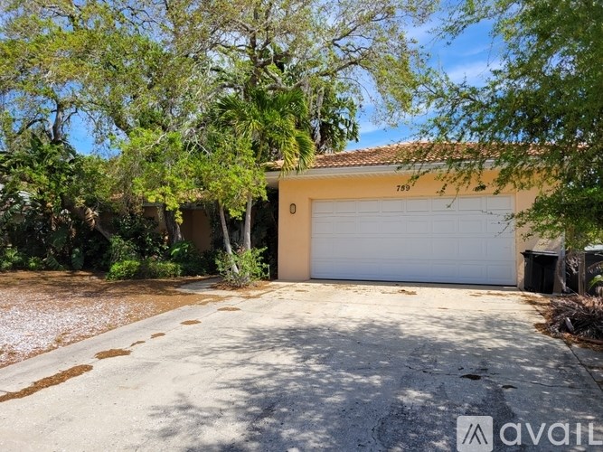 A house with a white garage door is surrounded by greenery.