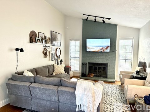 A living room with a grey couch and a fireplace.