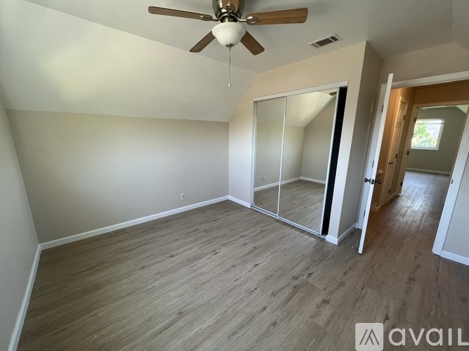A room with a ceiling fan and wooden flooring.