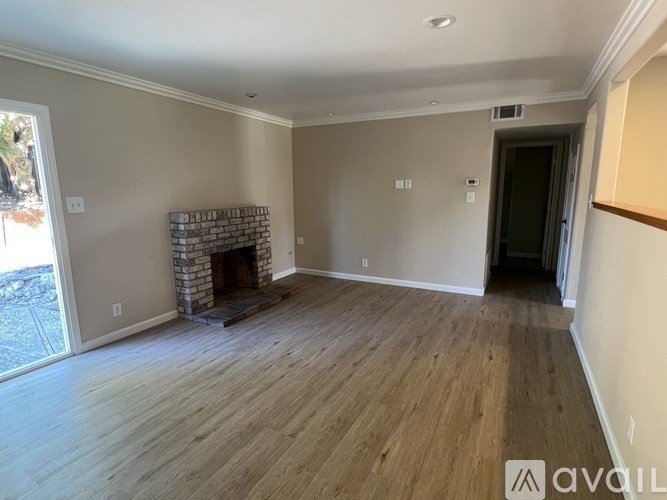 A living room with a fireplace and wooden floors.