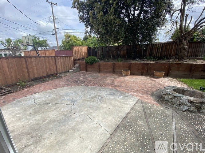 A backyard with a concrete patio and a wooden fence.