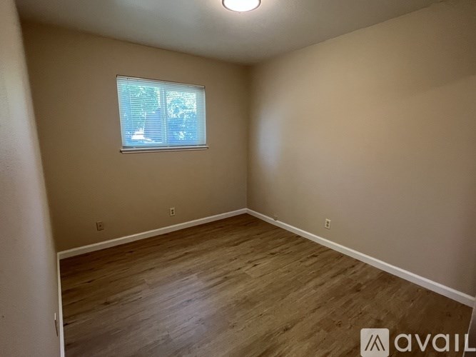 A room with wooden flooring and a window with blinds.