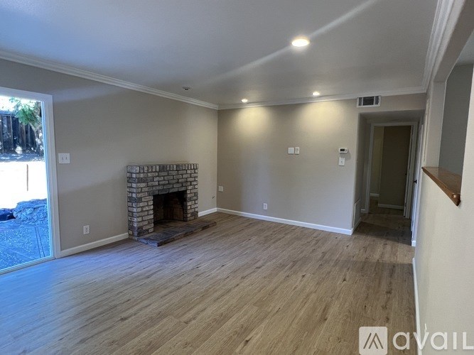 A living room with a fireplace and wooden floors.