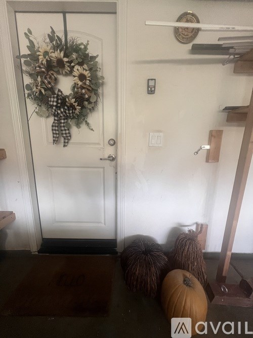 A door with a wreath and a pumpkin on the floor.
