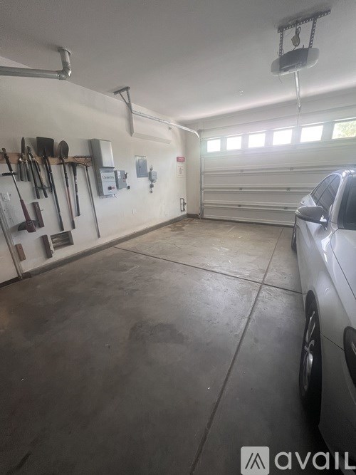 A garage with a car parked and a wall of tools.
