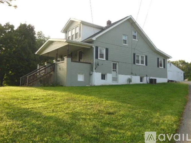 A house with a grey and white exterior is surrounded by a grassy lawn.