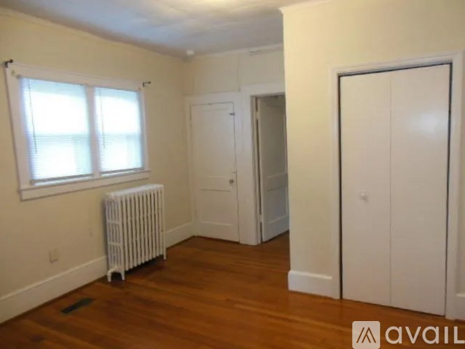 A room with a white radiator and wooden floors.