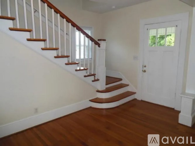 A wooden staircase with white railings leads up to a white door.