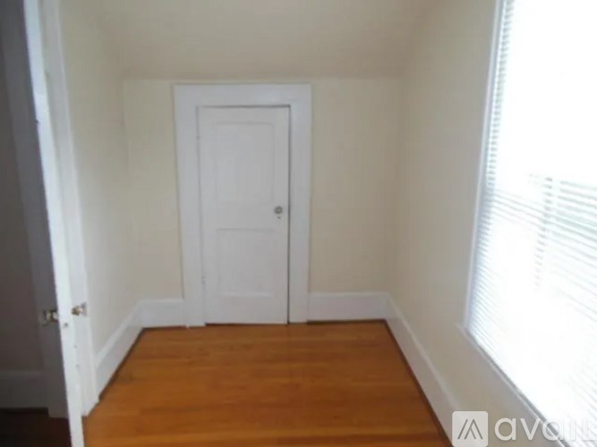 A white door is in a room with wooden floors.
