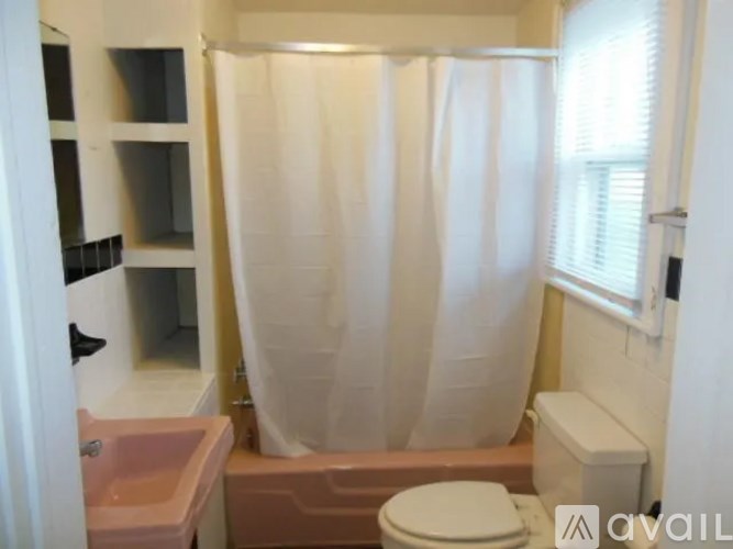 A bathroom with a toilet, sink, and shower curtain.