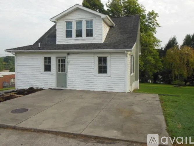 A white house with a grey roof and a green door.