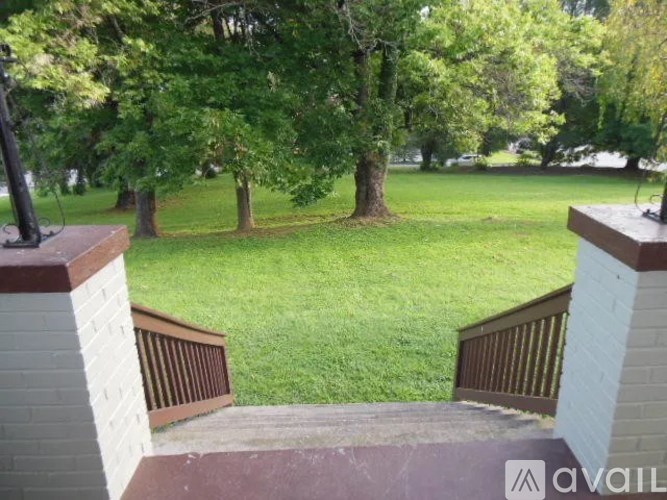 A view from a balcony overlooking a green lawn and trees.