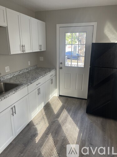 A kitchen with white cabinets and a black fridge.