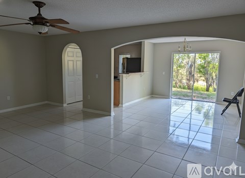 A spacious room with a ceiling fan and a sliding glass door leading to a backyard.