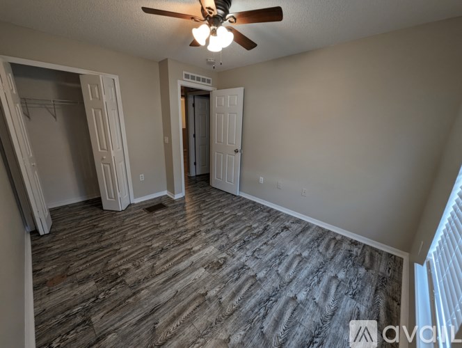 A room with a ceiling fan and wood flooring.