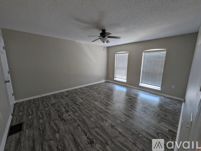 A room with a ceiling fan and wood flooring.