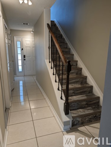 A hallway with a staircase and a white door.