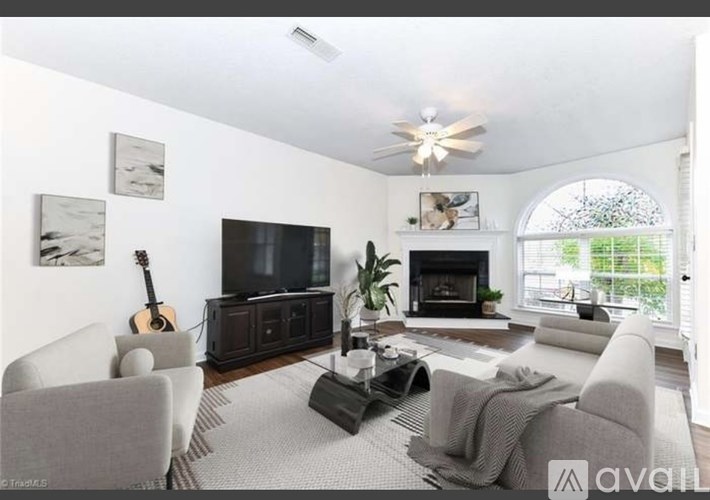 A living room with a fireplace, a television, and a guitar on the wall.
