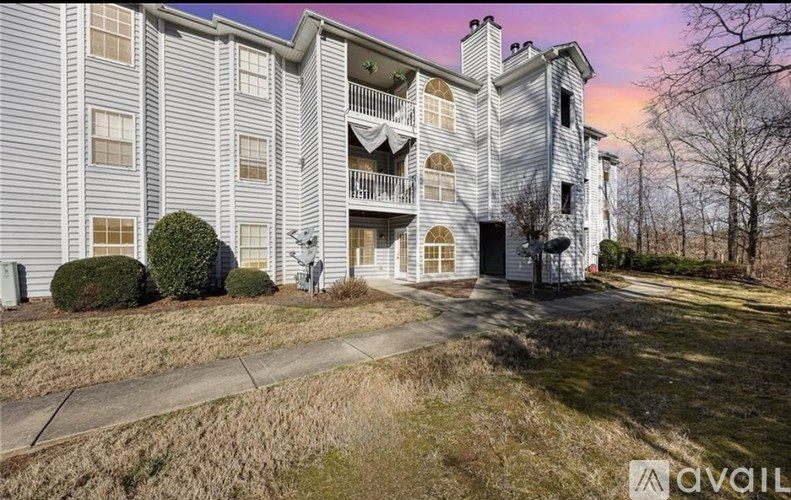 A large apartment building with a balcony and a small garden in front.