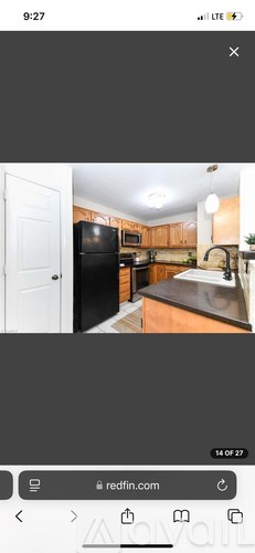 A kitchen with a black refrigerator and wooden cabinets.
