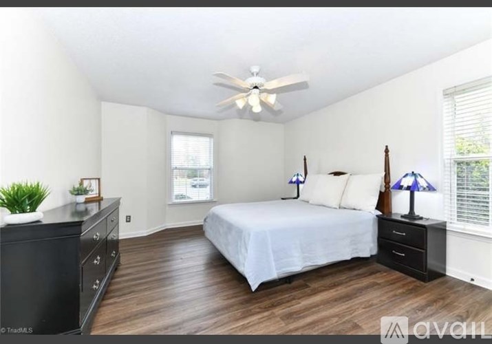 A bedroom with a bed, dresser, and ceiling fan.