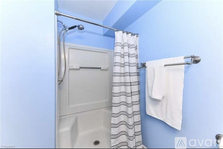 A white towel hangs on a silver towel rack in a blue bathroom.