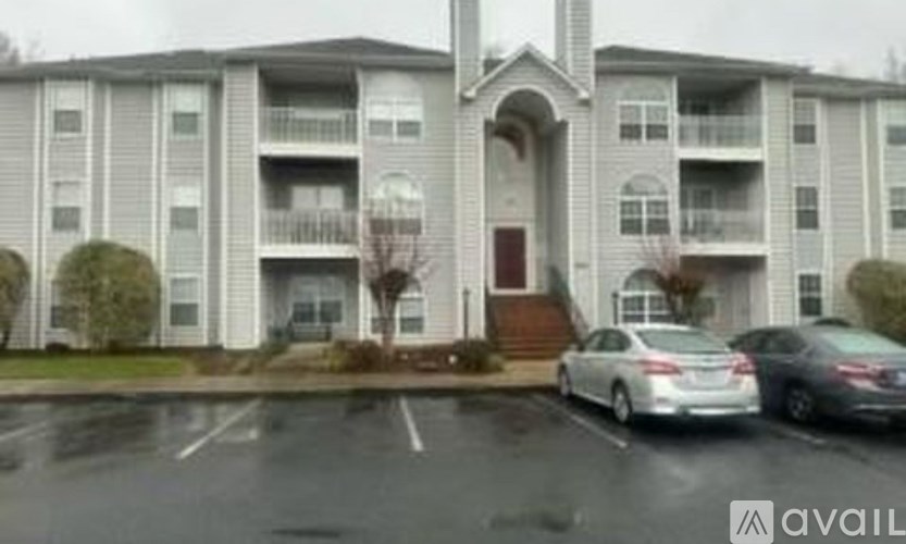 A car is parked in front of a building with a balcony.