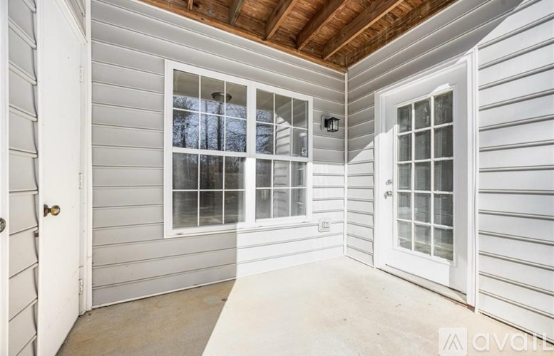 A room with a white door and a window with a view of trees.